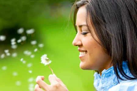 Une belle femme soufflant sur une fleur et souriant